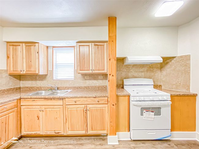 Kitchen featuring white gas range, custom range hood, light brown cabinetry, light countertops, and decorative backsplash | Image 13