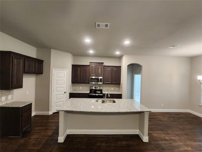 Kitchen with backsplash, appliances with stainless steel finishes, dark hardwood / wood-style floors, sink, and a kitchen island with sink | Image 3