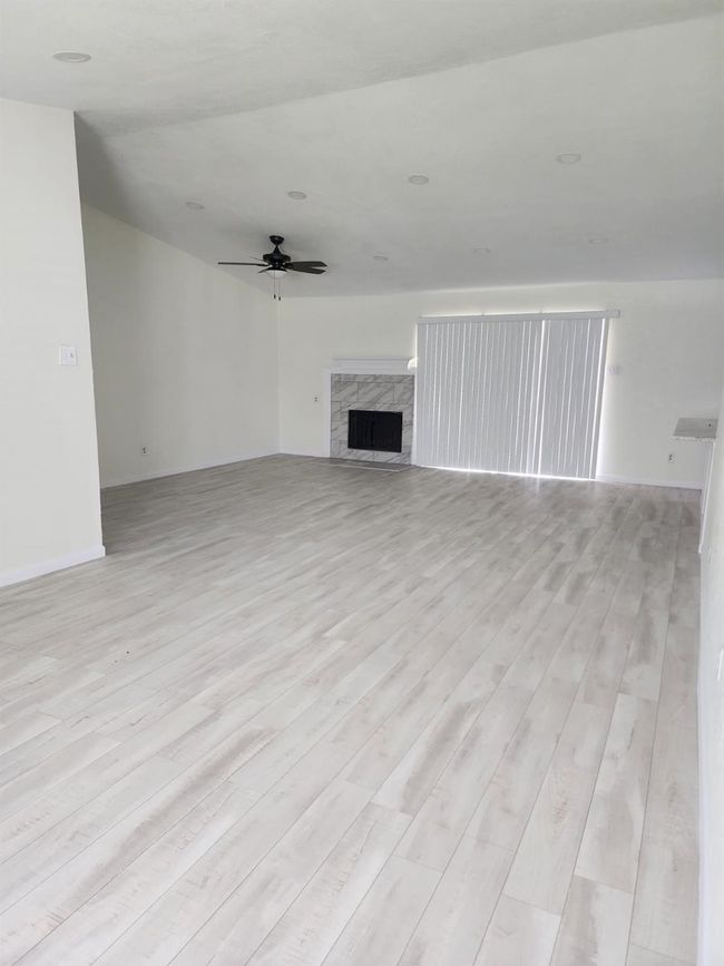 Unfurnished living room with ceiling fan, light wood finished floors, a fireplace, and baseboards | Image 28