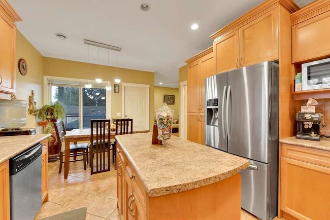 Kitchen featuring stainless steel appliances, light tile patterned floors, a center island, hanging light fixtures, and recessed lighting | Image 23