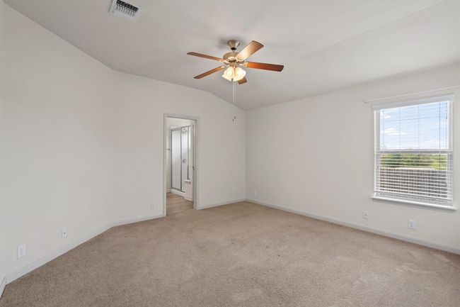 Spacious primary bedroom with a lofted ceiling and view of the back yard. | Image 11