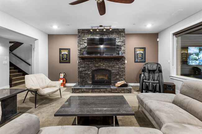 Living room with a stone fireplace, recessed lighting, baseboards, stairway, and rail lighting | Image 25