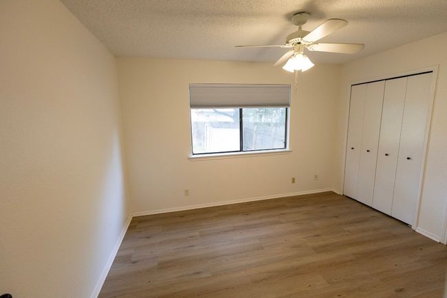Unfurnished bedroom with wood finished floors, a textured ceiling, a closet, and baseboards | Image 23