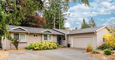 Nestled among mature trees that are stunning in their array of colors. Abundant windows and doors allow plenty of natural light. Two car attached garage offers a man door to back/side garden area. | Image 1