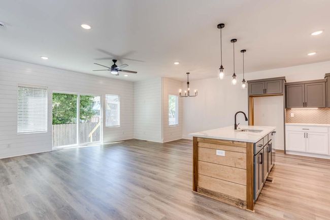 Kitchen featuring a sink, ceiling fan, open floor plan, tasteful backsplash, and light wood-type flooring | Image 5
