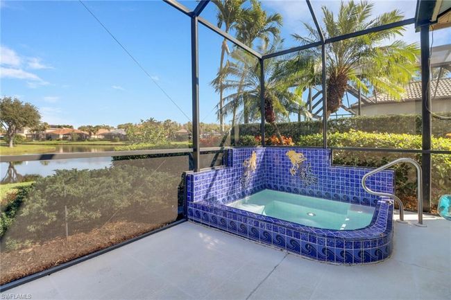 View of pool featuring a patio, a water view, glass enclosure, and an in ground hot tub | Image 24