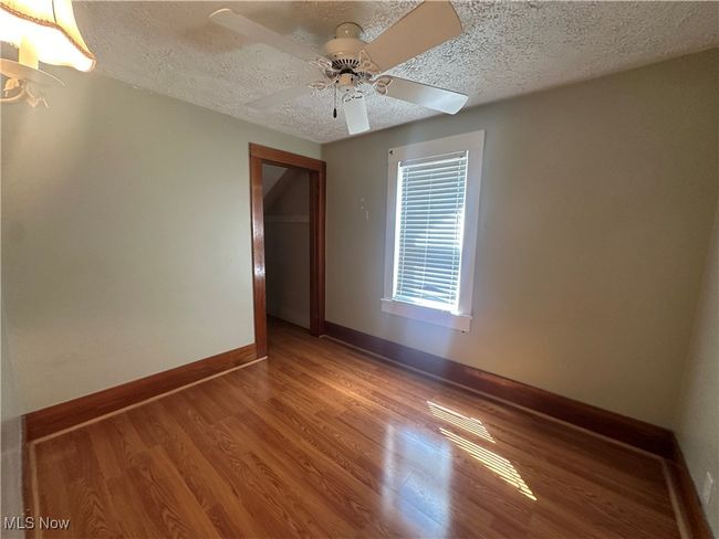 Empty room with wood finished floors, a textured ceiling, a ceiling fan, and baseboards | Image 17