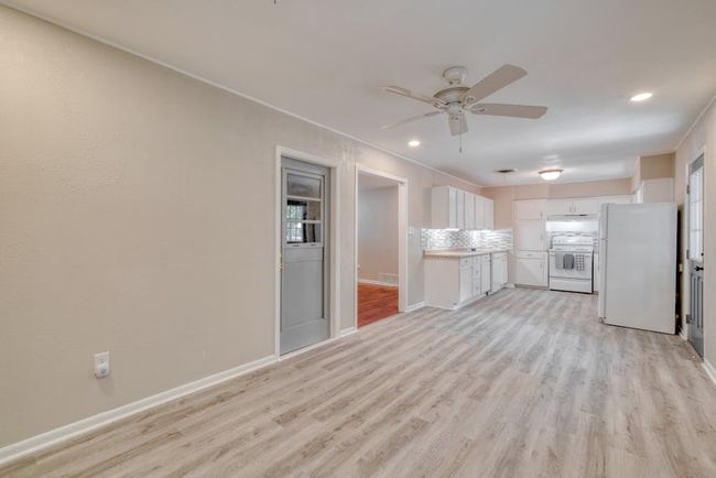 Kitchen with white cabinets, range, freestanding refrigerator, laminate countertops, and light laminate plank floors | Image 10