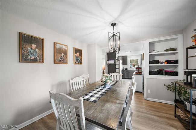 Dining space with a notable chandelier, wood finished floors, and baseboards | Image 6