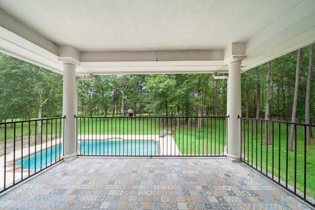 Covered balcony overlooking the pool and lush backyard | Image 37