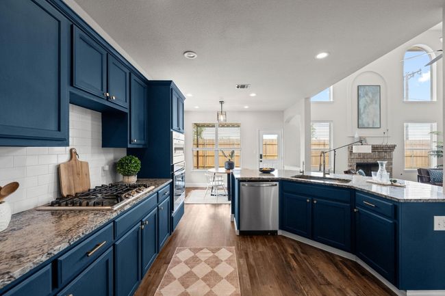 Kitchen featuring stainless steel appliances, a sink, blue cabinets, dark wood-type flooring, and recessed lighting | Image 7