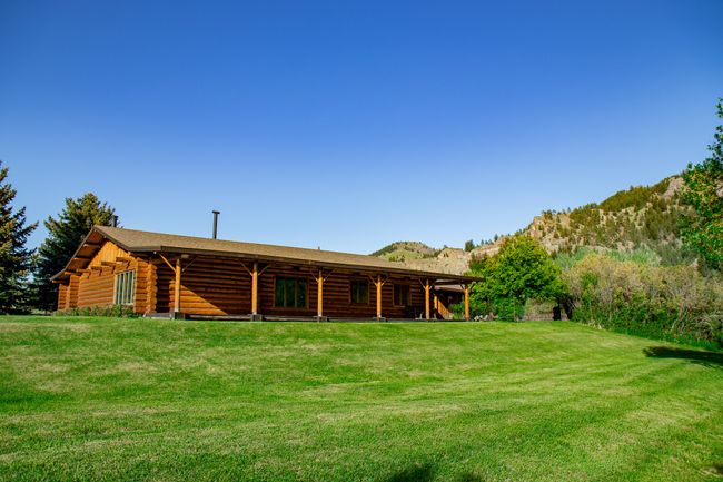 Rear view of house with log exterior, a mountain view, and a yard | Image 54