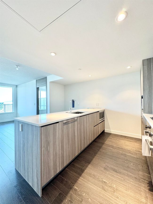 Kitchen with a sink, baseboards, modern cabinets, wood finished floors, and light countertops | Image 4
