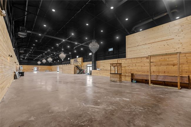Main event featuring a high ceiling, concrete flooring, a chandelier, and wood walls | Image 20