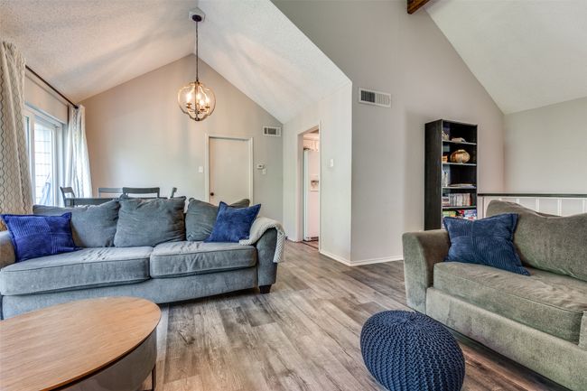 Living room featuring a chandelier, wood finished floors, baseboards, high vaulted ceiling, and beam ceiling | Image 4