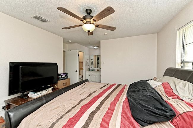 Bedroom featuring ceiling fan, ensuite bathroom, and a textured ceiling | Image 14