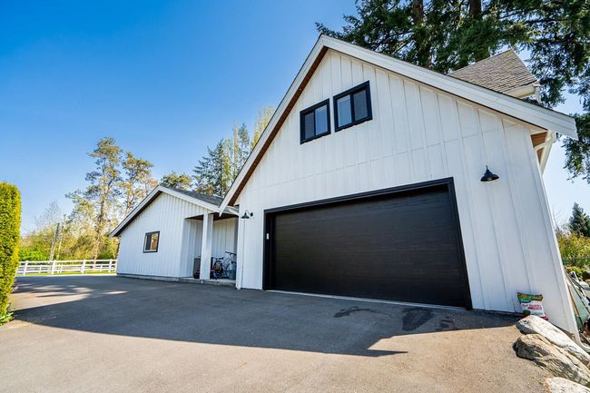 View of property exterior with fence, roof with shingles, board and batten siding, and a garage | Image 28