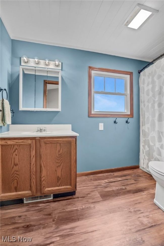 Bathroom with wood finished floors, toilet, vanity, baseboards, and visible vents | Image 27