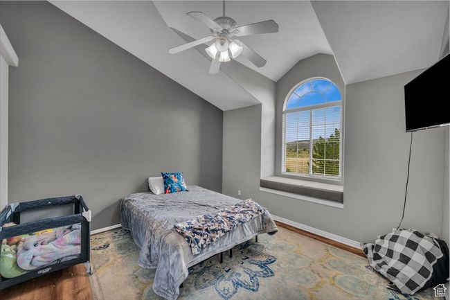 Bedroom with ceiling fan, lofted ceiling, baseboards, and wood finished floors | Image 22