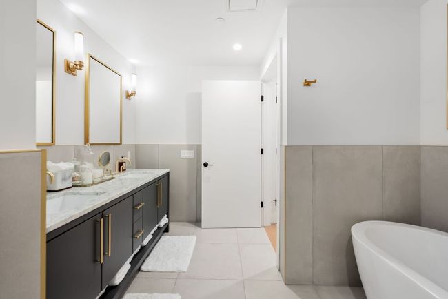 Gorgeous marble bathroom with dual-vanities, a soaking tub, and stunning gold finishes. | Image 22