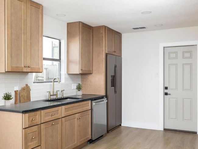 Kitchen with visible vents, light wood-style flooring, a sink, appliances with stainless steel finishes, and tasteful backsplash | Image 14