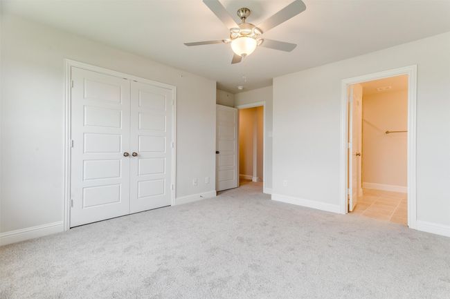 Unfurnished bedroom featuring connected bathroom, light colored carpet, a closet, and ceiling fan | Image 18