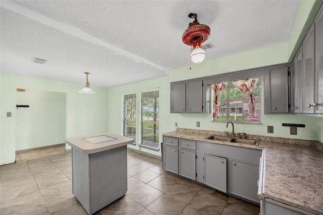 Inviting kitchen with ample natural light flows seamlessly to the entry, featuring modern cabinetry and a functional island for easy entertaining. | Image 16