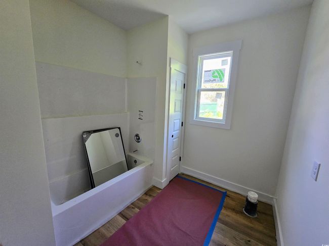 Full bathroom featuring wood finished floors, a tub, and baseboards | Image 27