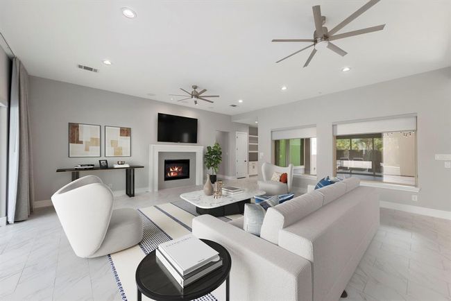 This elegant living room invites you to unwind by the modern fireplace, with sleek tile floors, custom window coverings, ample recessed lighting and a spacious layout perfect for entertaining. *This photo has been virtually staged.* | Image 15