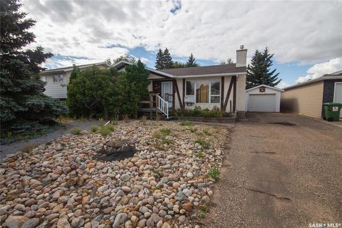 Exterior featuring decorative half-timbering, a concrete driveway, a detached garage, and a front rock garden | Card Image