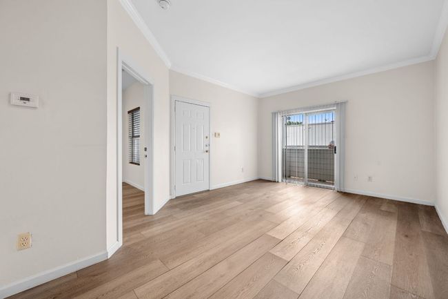 Living area with crown molding, wood finished floors, and baseboards | Image 4