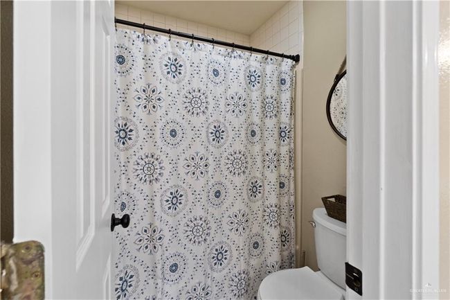 Bathroom featuring toilet and curtained shower | Image 9