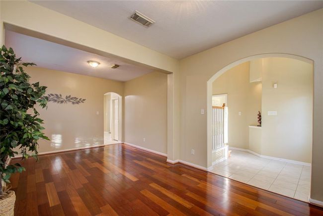 This photo showcases a bright, open living area with rich hardwood floors, neutral-colored walls, and elegant archways. The space is enhanced by natural light, making it inviting and spacious. | Image 9