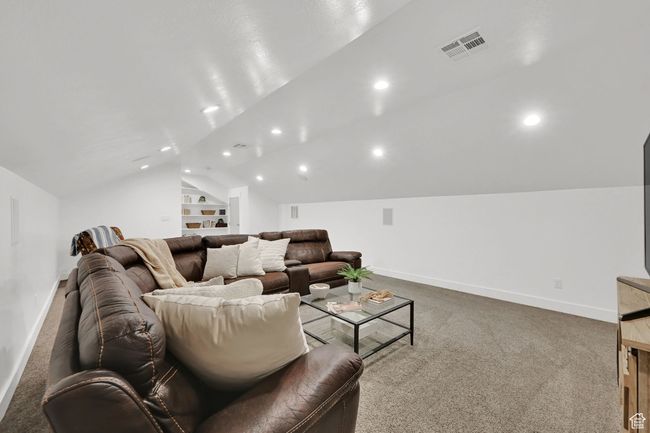 Carpeted home theater room with lofted ceiling, recessed lighting, and built in shelves | Image 35