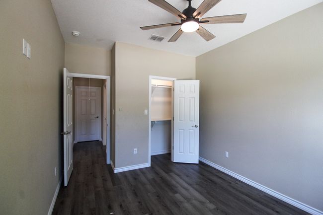 Unfurnished bedroom featuring dark wood-style floors, ceiling fan, and a closet | Image 14