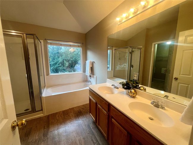 Full bath with a shower stall, a garden tub, wood finished floors, lofted ceiling, and double vanity | Image 26