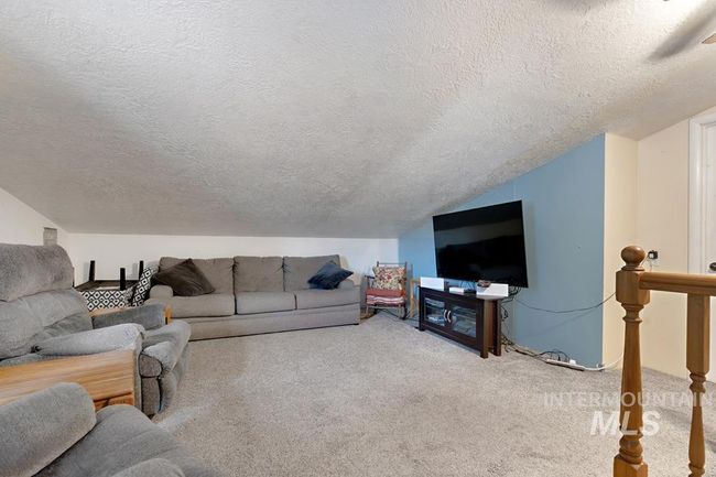 Living room with a textured ceiling, carpet, and lofted ceiling | Image 24