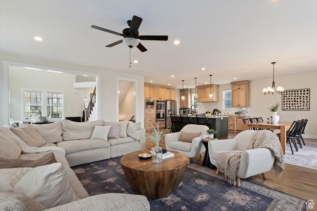 Living area featuring recessed lighting, wood finished floors, stairs, and ceiling fan with notable chandelier | Image 7