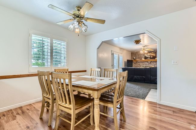 Dining area with a ceiling fan, light wood-style flooring, and arched walkways | Image 7