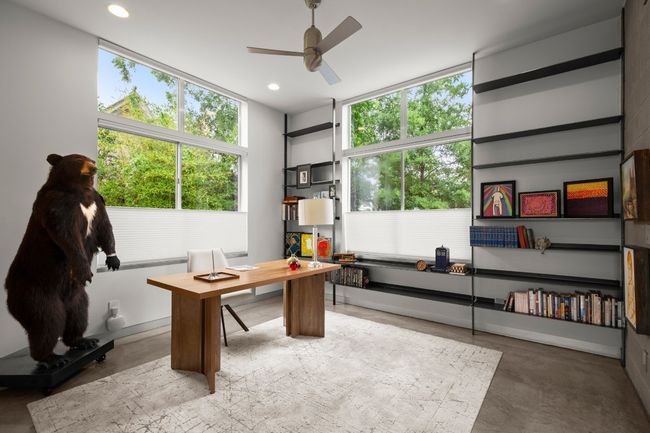 Office/Secondary bedroom at the front of the home, with built in steel bookshelves, a luxury soaking tub in the ensuite bathroom and custom art on the door. | Image 21