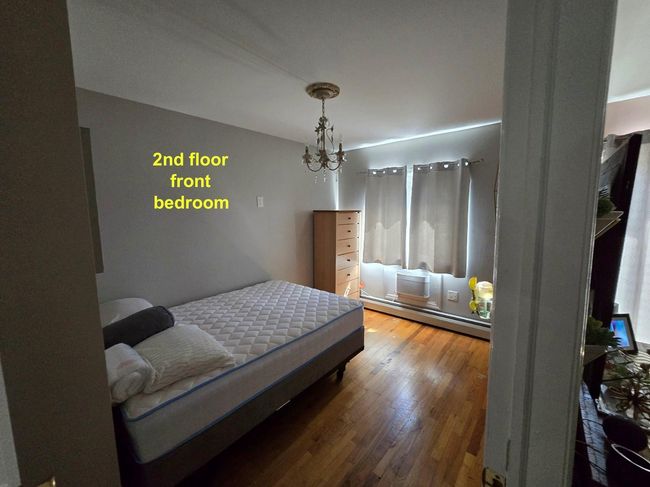 Bedroom with baseboard heating, a chandelier, and hardwood / wood-style floors | Image 12
