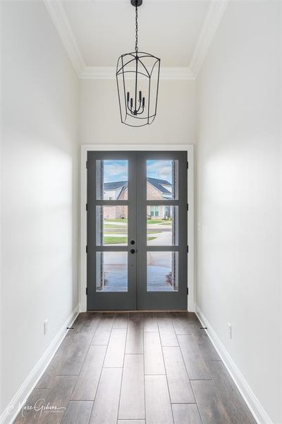 Entryway featuring wood-type flooring, crown molding, french doors, and an inviting chandelier | Image 3