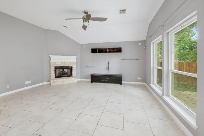 Unfurnished living room featuring light tile patterned floors, ceiling fan, visible vents, and lofted ceiling | Image 6