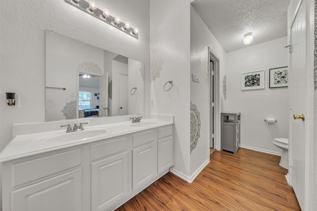 Full bathroom with double vanity, wood finished floors, and a textured ceiling | Image 13