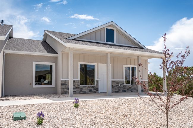 Rear view of house featuring a porch, board and batten siding, a shingled roof, and stone siding | Image 7