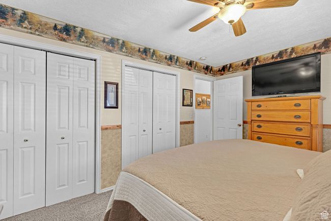 Bedroom featuring multiple closets, carpet flooring, a textured ceiling, a wainscoted wall, and ceiling fan | Image 14