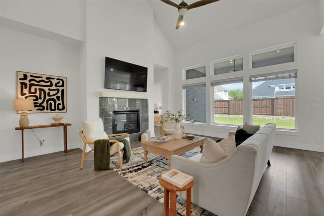 Living area featuring baseboards, high vaulted ceiling, a ceiling fan, wood finished floors, and a fireplace | Image 6