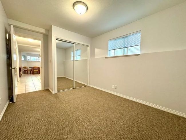 Unfurnished bedroom featuring carpet floors, a closet, and multiple windows | Image 6