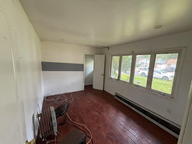 Spare room featuring dark wood-style floors and a baseboard radiator | Image 4