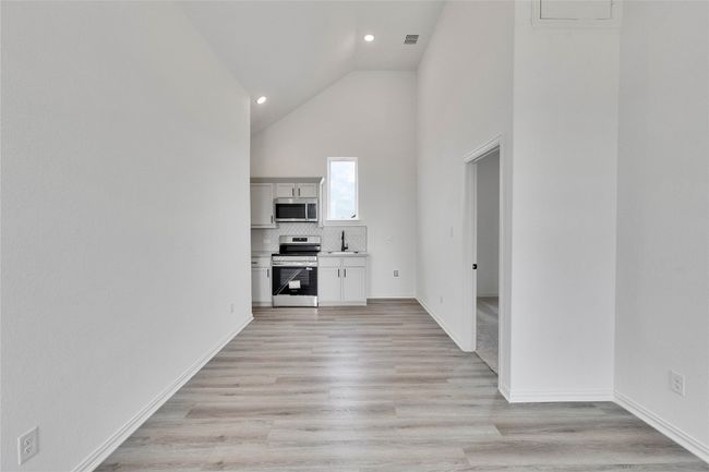 Unfurnished living room featuring high vaulted ceiling, light wood-style floors, and recessed lighting | Image 14